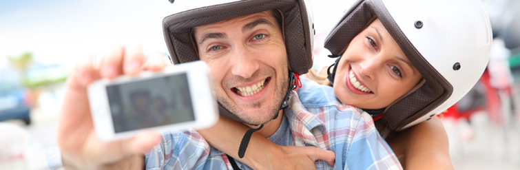 Two Tourists On Scooter With Helmets Taking A Selfie