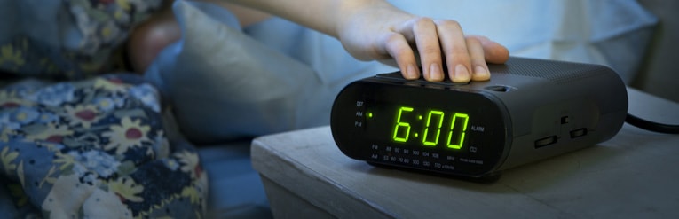 person turning alarm clock off to get up for work 
