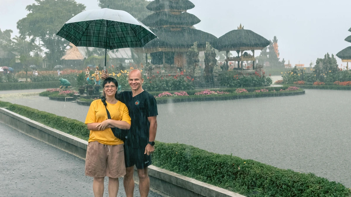 couple standing in bali, in the rain, with an umbrella